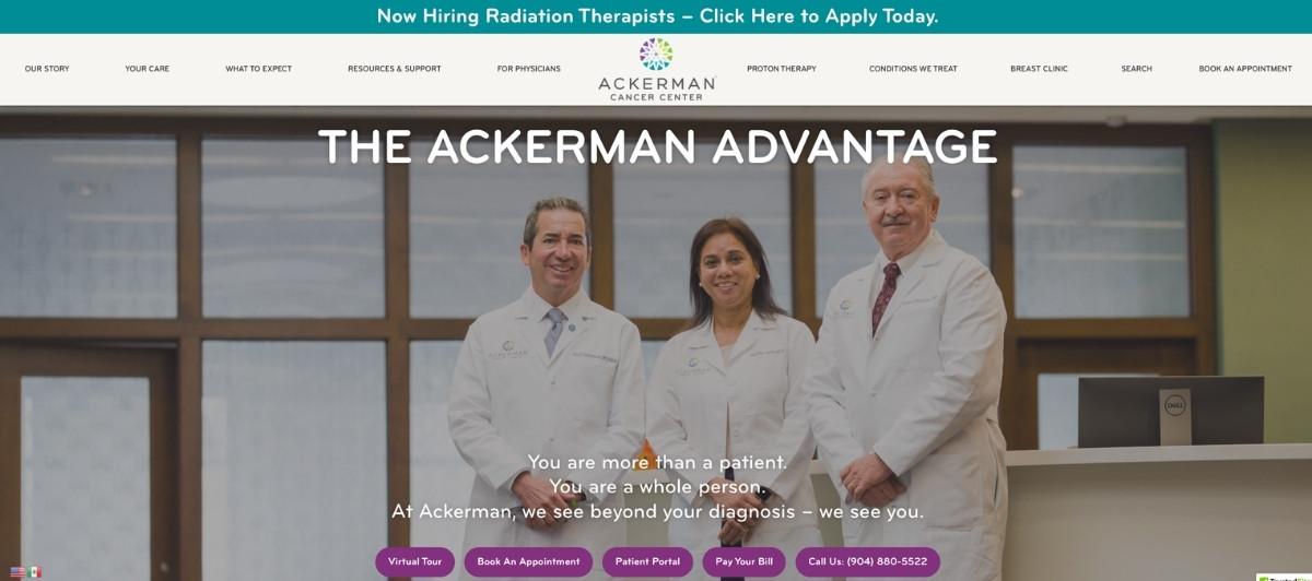 Three physicians in white coats stand in a hospital lobby with a reception desk; the headline reads 'The Ackerman Advantage' and the Ackerman Cancer Center branding is visible.