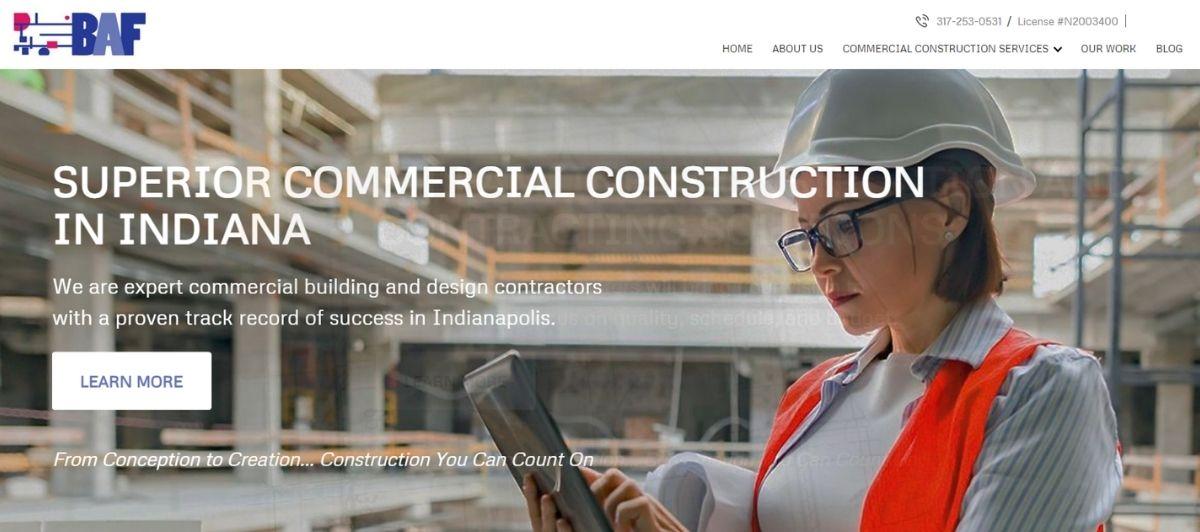 Female construction engineer in a hard hat and orange safety vest uses a tablet on a construction site; hero image for a commercial contractor in Indiana.