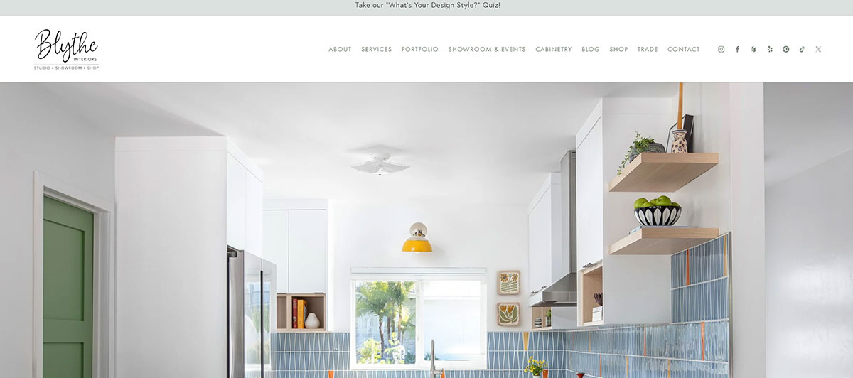Bright modern kitchen with white cabinets, blue tile backsplash, open wooden shelves, and a window letting in natural light.