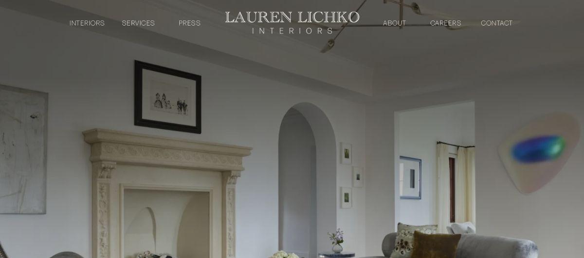 Living room interior with a carved white fireplace, arched doorway, and a gray sofa; homepage image for Lauren Lichko Interiors.