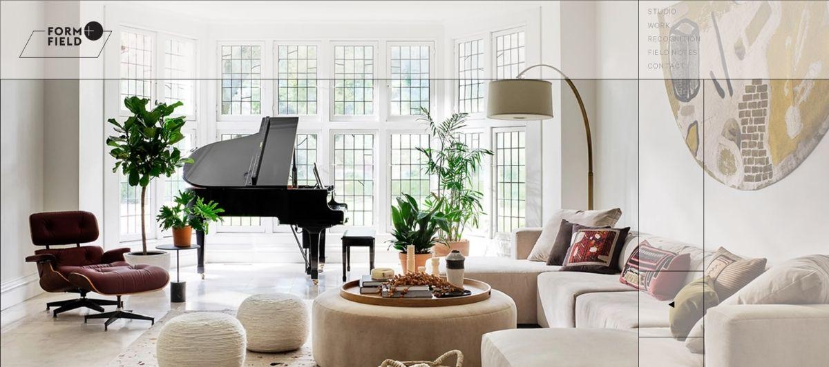 Bright living room with a black grand piano, beige sectional sofa, and abundant greenery by large windows.