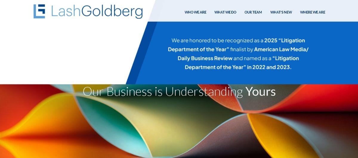 LashGoldberg law firm hero: logo and navigation at top, blue award banner in the middle, and a colorful abstract folded-paper background with the slogan 'Our Business is Understanding Yours'.