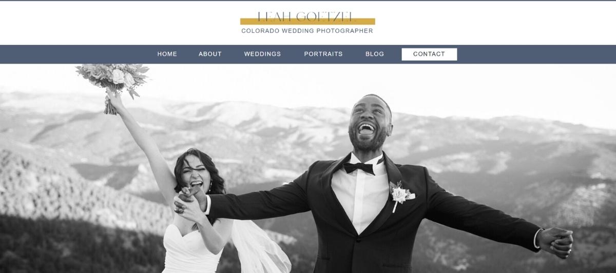 Bride and groom laugh together, arms raised, outdoors with mountains in the background (black-and-white photo).