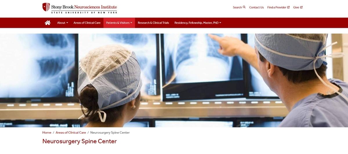 Two surgeons in scrubs review spinal X-ray images on monitors in a spine center.