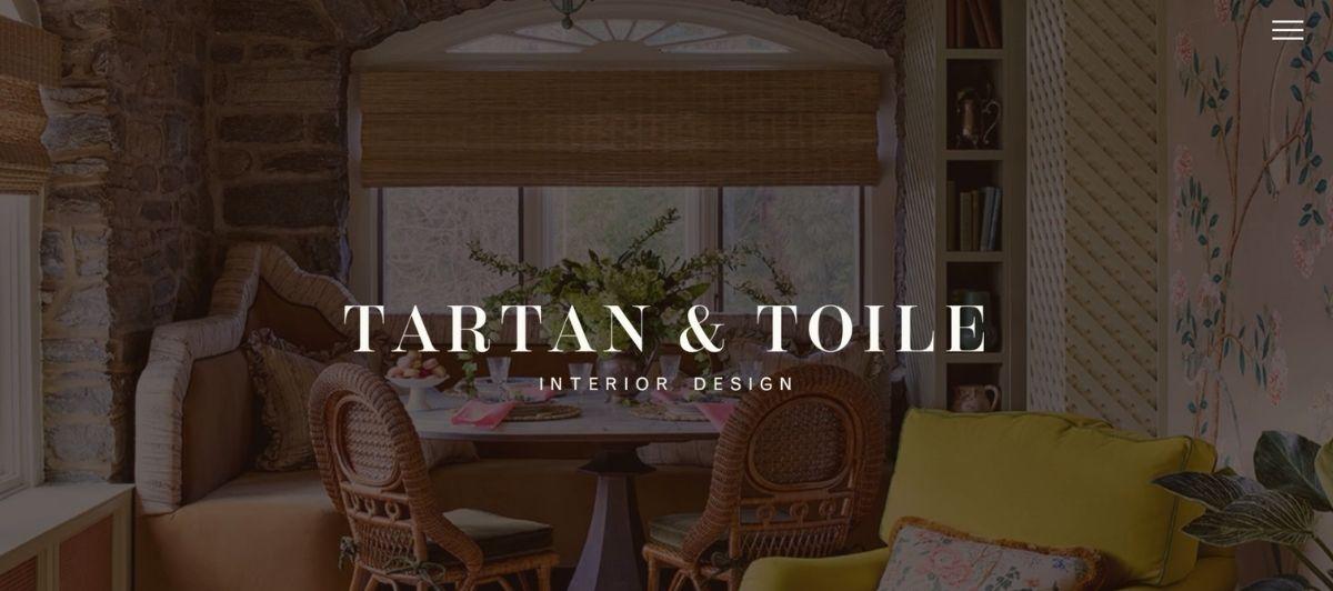 Interior design scene with stone walls, wicker chairs around a table, plants, and the text 'TARTAN & TOILE INTERIOR DESIGN'.