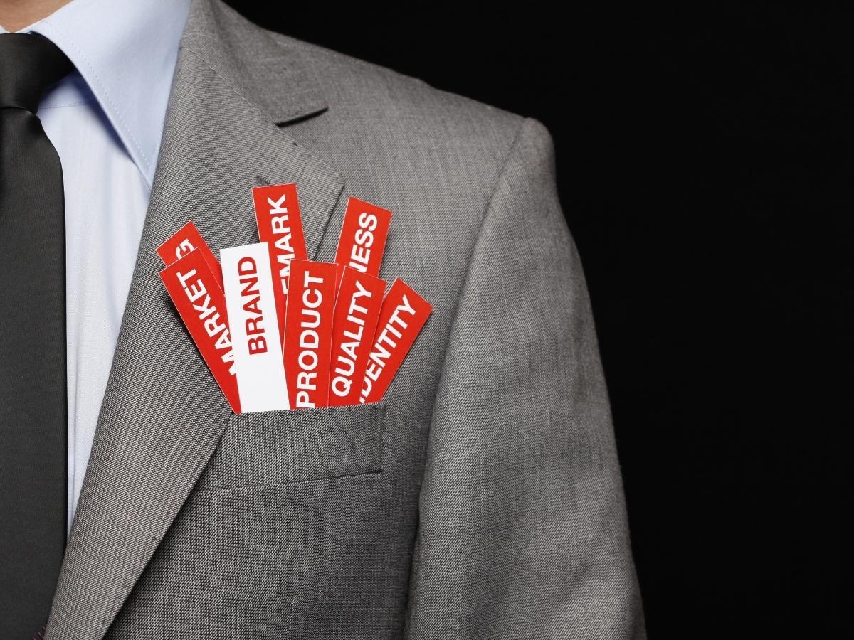 Gray suit pocket with red-and-white tags labeled Brand, Market, Product, Quality, Identity inset in the pocket