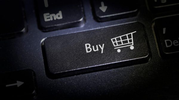 Keyboard key labeled Buy with a white shopping cart icon beside it on a dark keyboard surface, implying an online purchase action.
