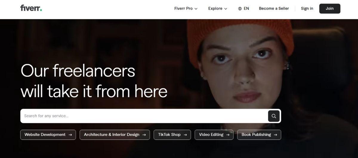 Hero banner with a woman in a darkened setting, bold headline 'Our freelancers will take it from here' and a large search field with category chips below.