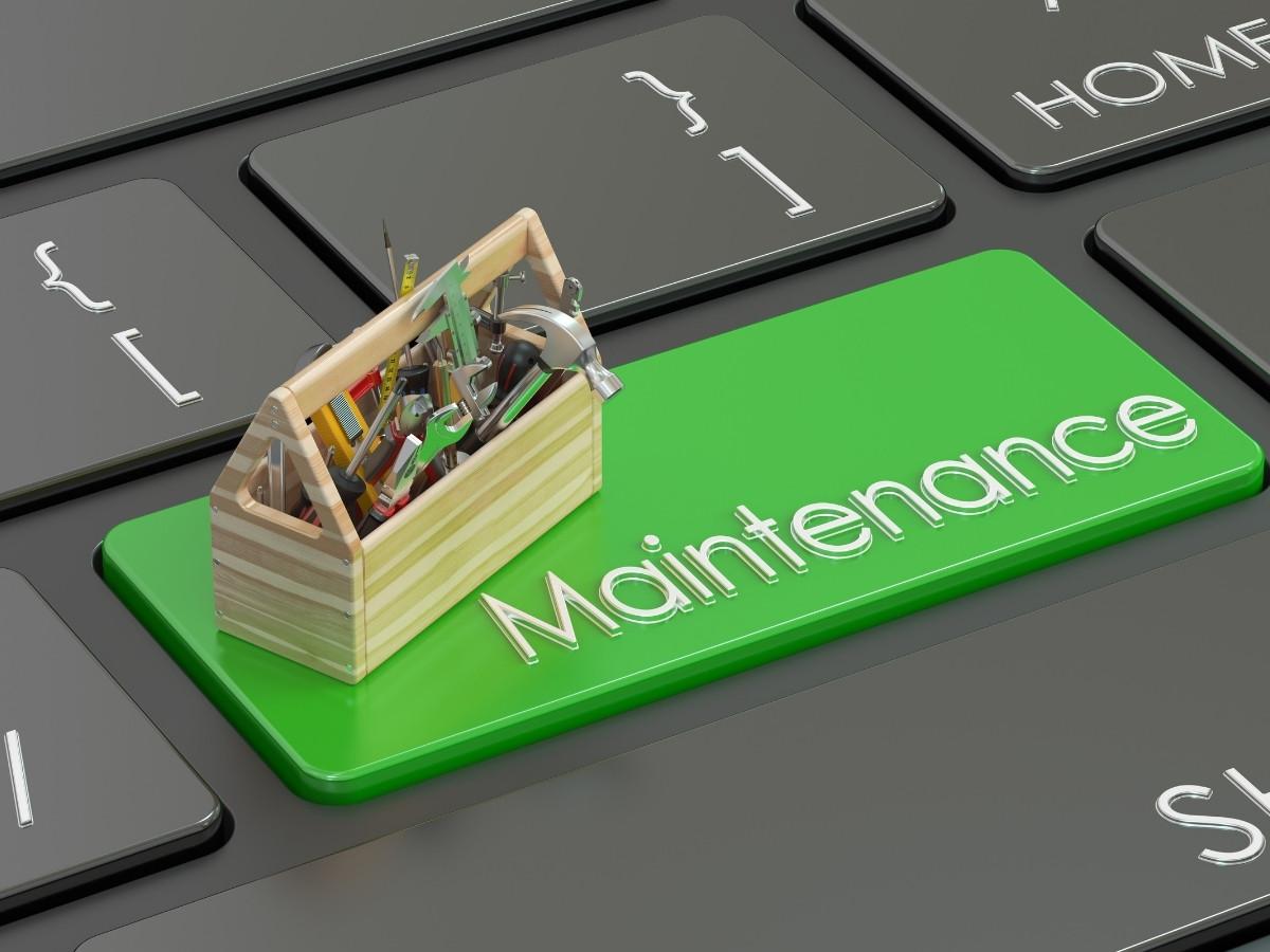 Green 'Maintenance' key on a keyboard with a wooden toolkit resting on it, symbolizing repair/maintenance tasks