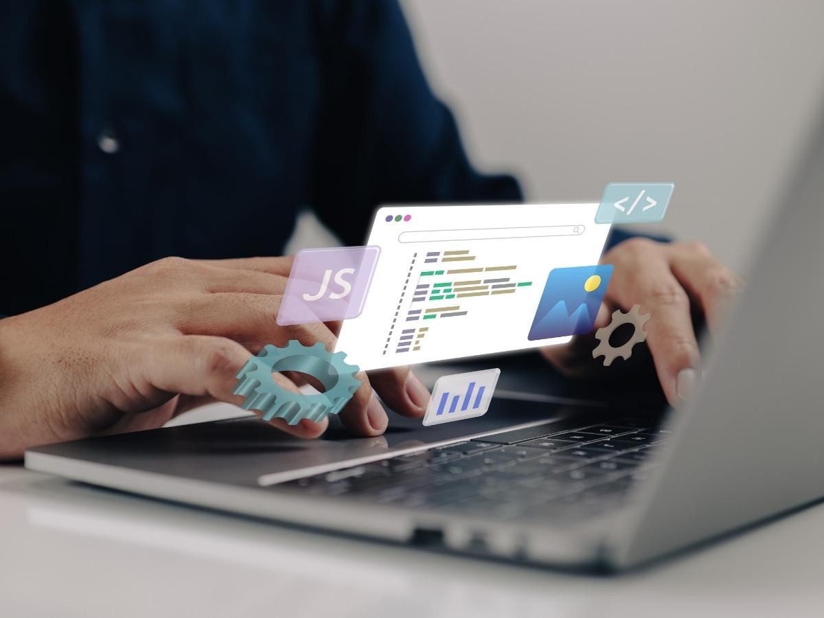 Hands typing on a laptop with floating code icons (JS, code, gears, charts) representing development tooling.