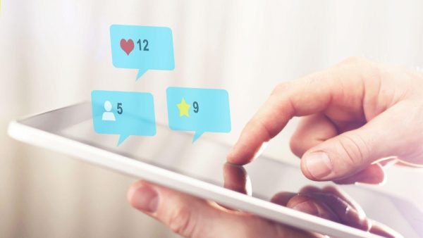Person using a tablet with floating blue notification bubbles showing likes (12), followers (5), and favorites (9).