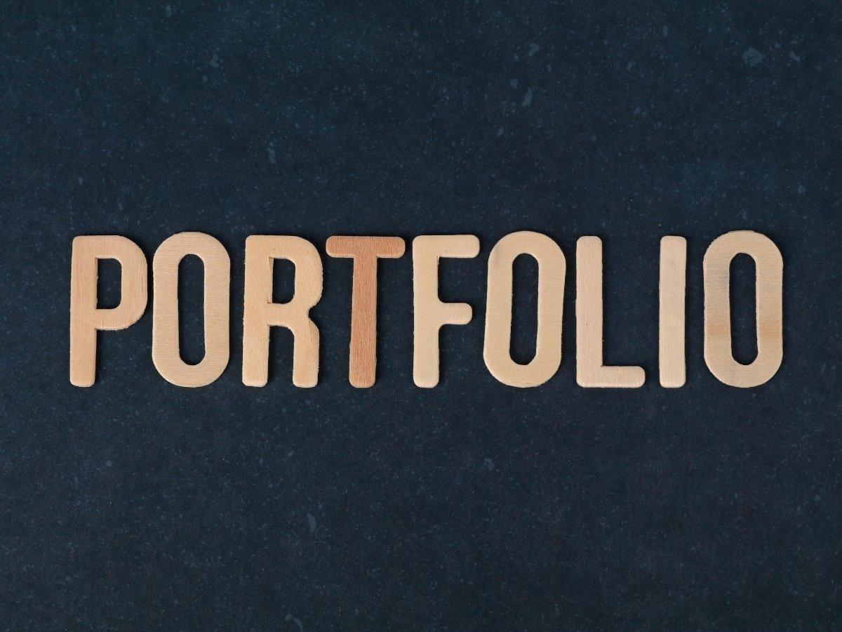 Wooden block letters spell PORTFOLIO on a dark textured background.