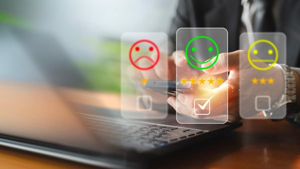 Interface with floating rating icons over a laptop, showing a green smiley for positive feedback.