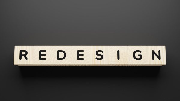 Wooden letter blocks spelling the word REDESIGN on a dark gray background.