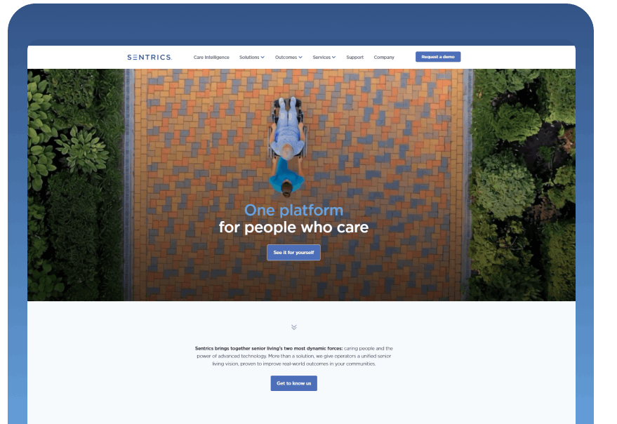 Aerial view of a person walking on a brick pathway edged by greenery, with the headline 'One platform for people who care' overlaid and a 'See it for yourself' button.