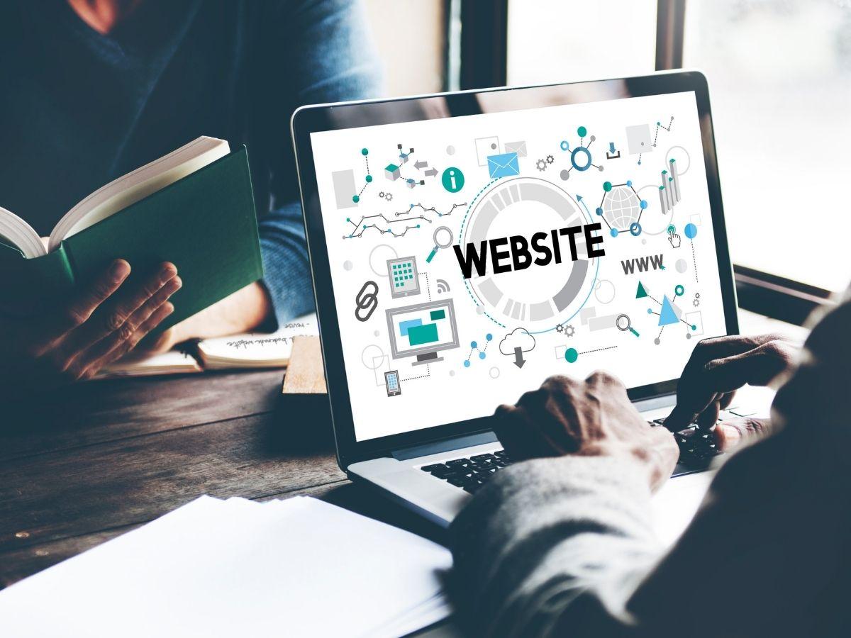 Person typing on a laptop screen that shows a 'WEBSITE' concept with icons, illustrating web design.