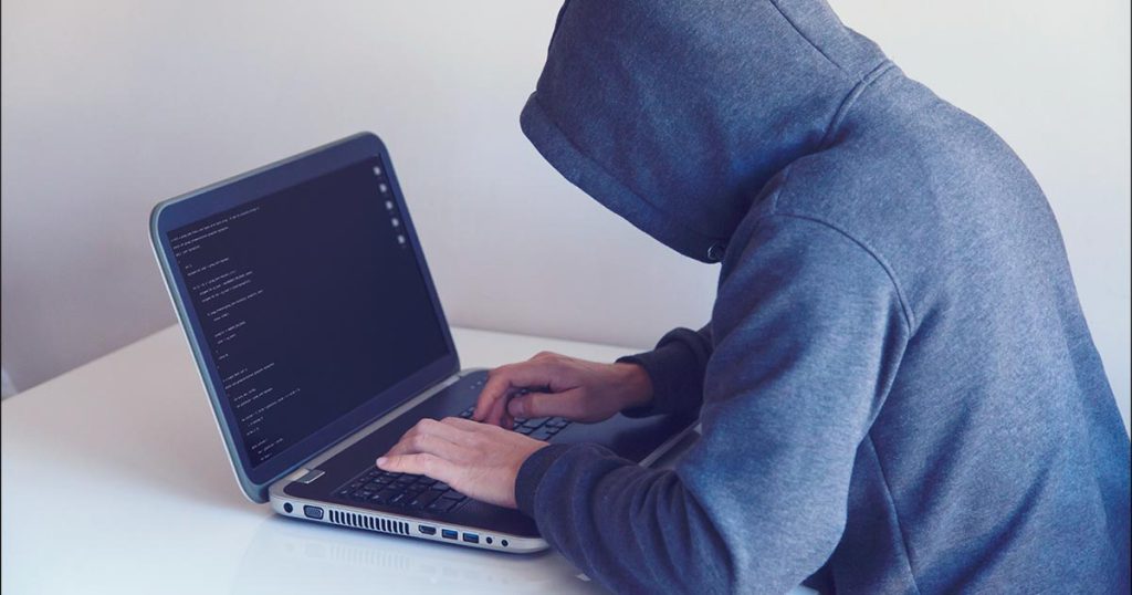 website hacker with hoodie, testing security of WordPress website on laptop