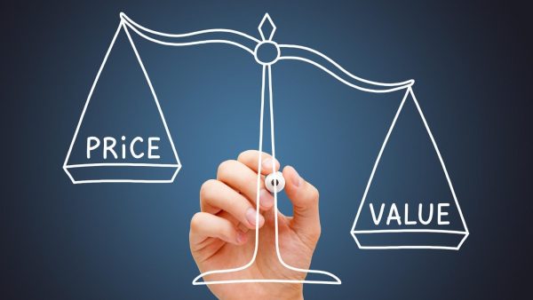 Hand drawing a scale balancing 'PRICE' and 'VALUE' to illustrate price vs value.