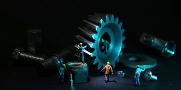 Miniature workers fixing mechanical parts